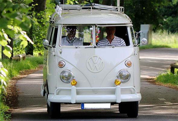 Zwei Männer fahren in einem weißen VW Bulli
